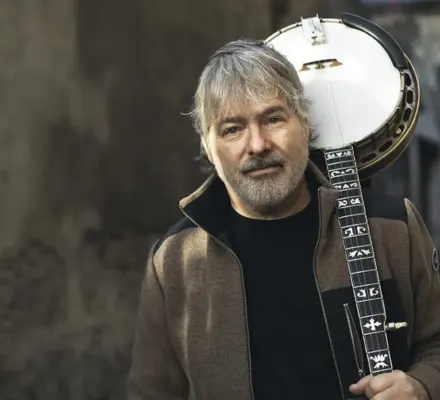 A man holds a banjo over his shoulder.