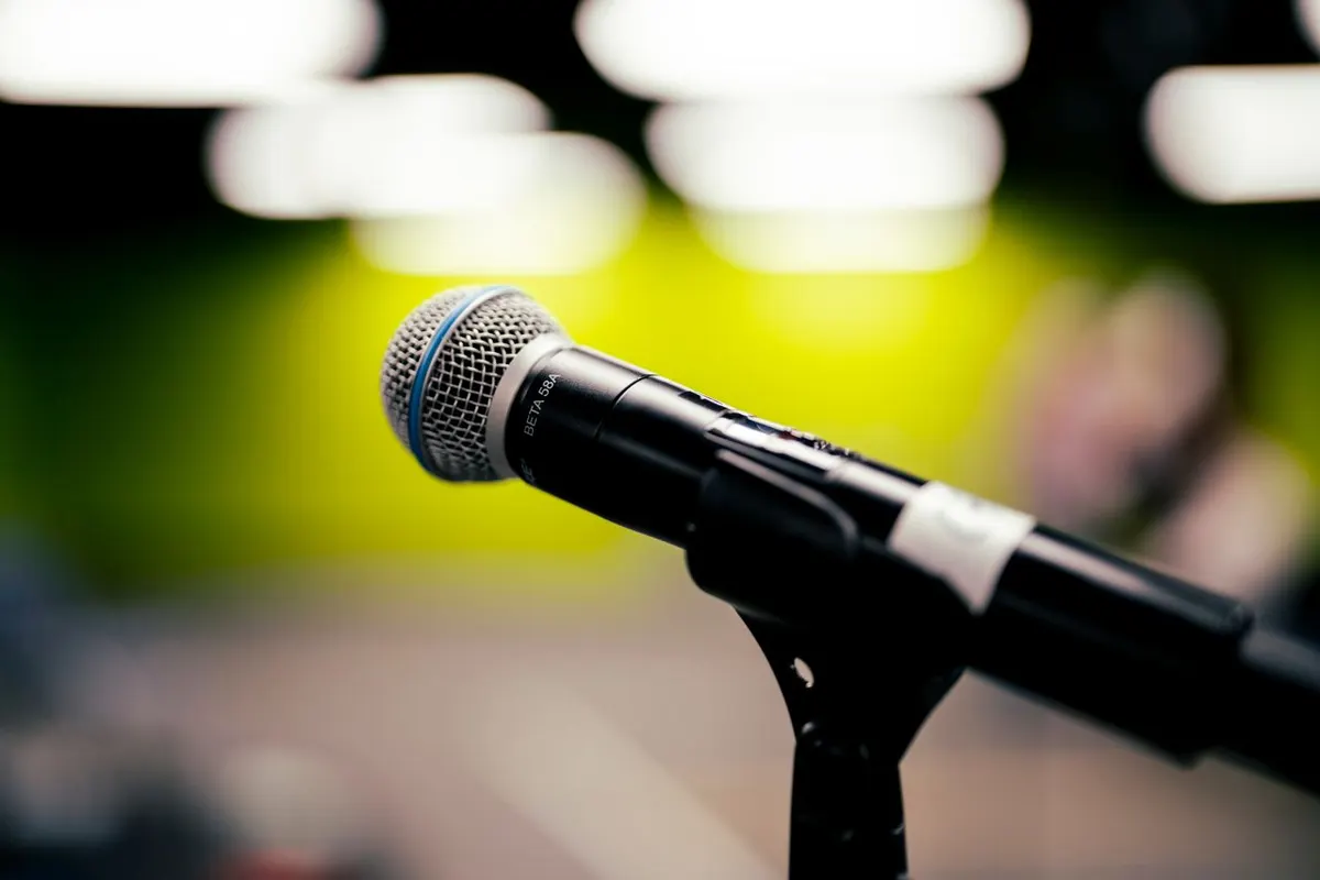 Microphone in focus in the foreground, and a yellow wall in the background